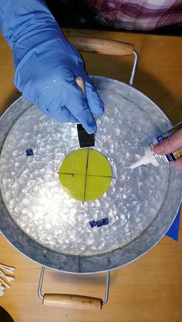 Carefully place the smaller glass pieces around the central circle, ensuring even spacing and using tweezers if needed.