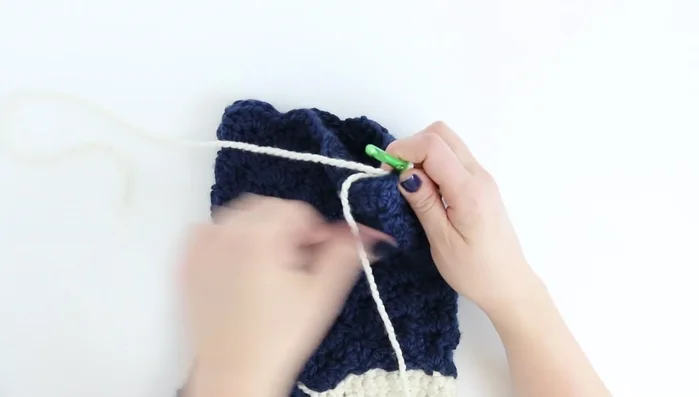 Cuff: Join first color. Chain 1, single crochet. Chain 18. Half double crochet in third chain from hook and continue across. Slip stitch into next two stitches on the stocking. Turn and half double crochet in back loops only across 16 stitches. Repeat, decreasing slip stitches as you go until cuff is desired length. Sew cuff closed.