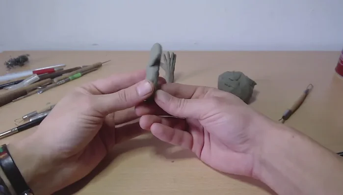 Create the hand 'glove': Connect the thumb to the palm, blending the clay for a smooth transition.