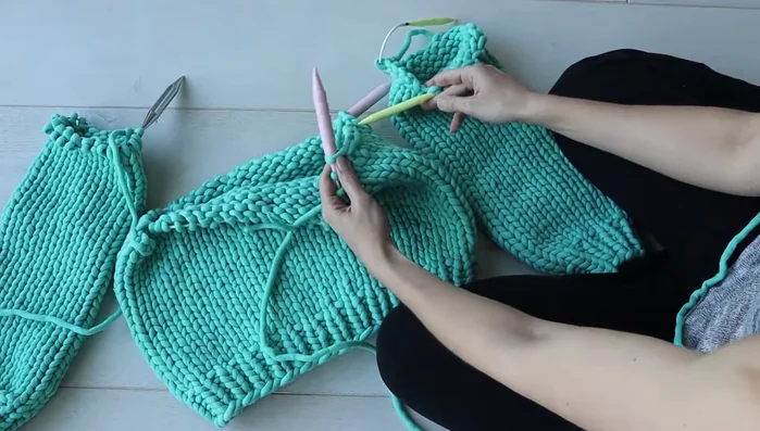 Work up to the bound-off stitches on one sleeve. Using the working yarn from the body, knit the sleeve stitches as a continuation of the body stitches, matching the bound-off stitches one-for-one. This creates the underarm seam.