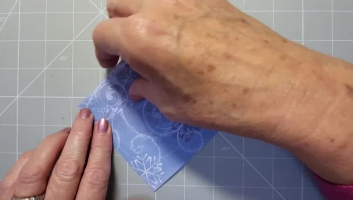 Bring the bottom triangle towards you, aligning the edges and reinforcing the crease.