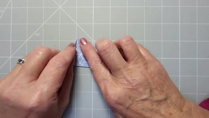 Bring the bottom triangle towards you, aligning the edges and reinforcing the crease.