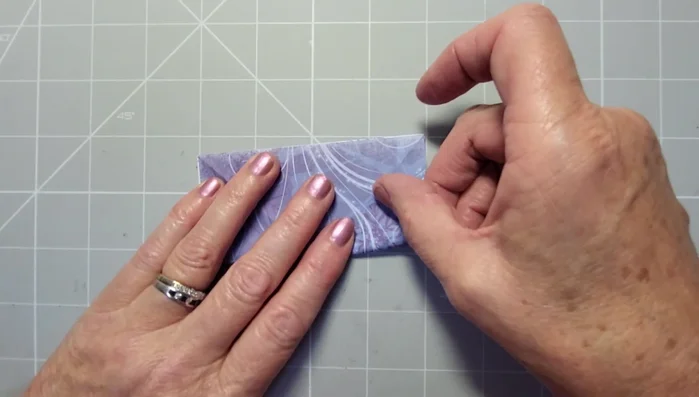 Pinch and fold the closed side over to the center line, creating a crease.