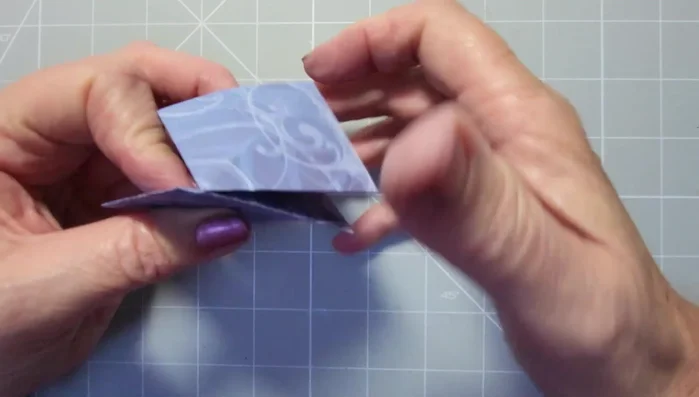 Repeat the fold on the other side. Then, open it up, reinforce the square shape by pinching the corners and folding inwards.