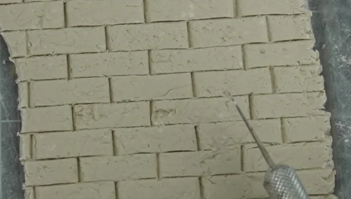 Create imperfections: lift away small areas of clay, cut out sections, and cut layers to simulate aged bricks.