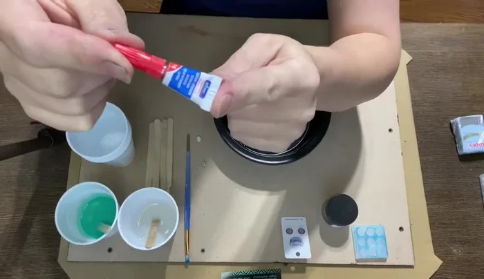 Secure the design to an empty takeout container using cheap glue to prevent it from floating during the mold-making process.