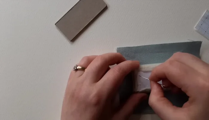 Cut 1cm strip of lightweight card, cover in fabric, and glue around cushion edges.