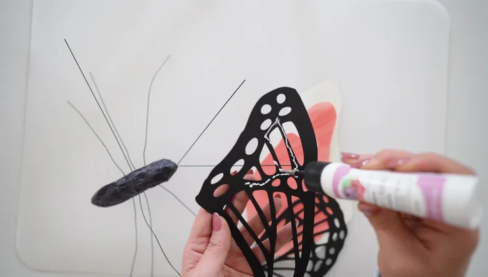 Glue the wing pieces together, starting with the black pattern, then the orange, and finally the white, following the order shown in the video.