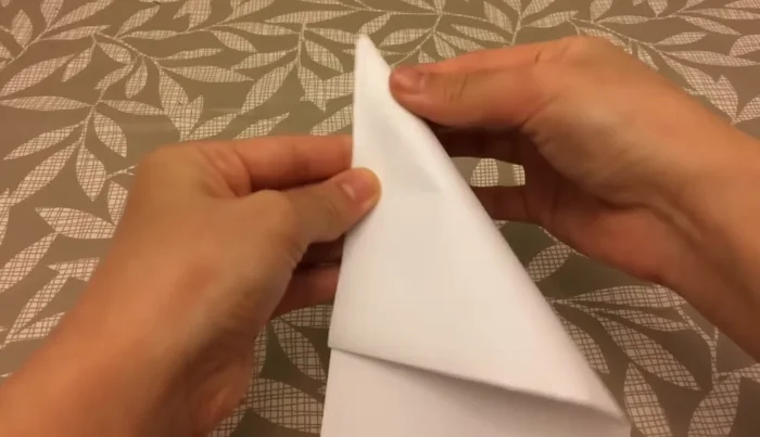 Fold one flap over to form a tiny triangle, then fold the remaining flap behind.