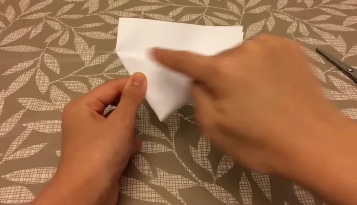 Fold one flap over to form a tiny triangle, then fold the remaining flap behind.