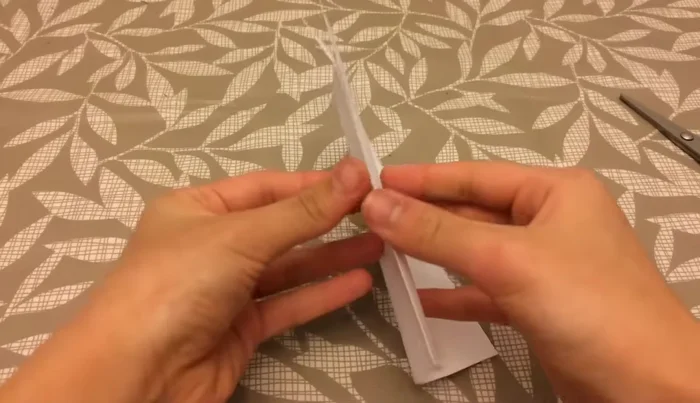 Fold one flap over to form a tiny triangle, then fold the remaining flap behind.