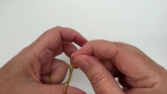 Insert needle tip through the slip knot and pull the working yarn (attached to the ball) to close the slip knot.