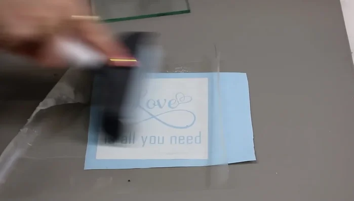 Roll over the stencil with a scraper to ensure it is firmly adhered and has no air bubbles.