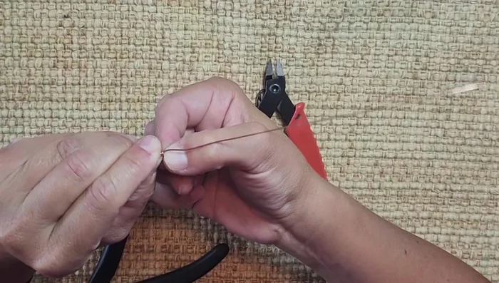 Wrap the wire around the stone, anchoring it at the bottom corner, then around the back, keeping the bale centered and tight. Bring the wire back to the front, around the back again, and anchor it at the top corner.