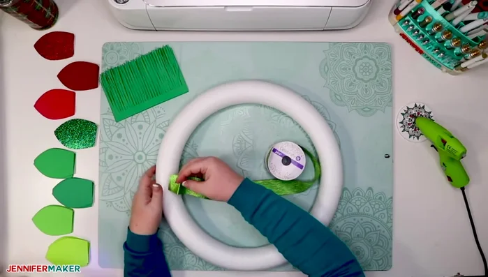 Wrap the foam wreath form with ribbon, securing the ends with hot glue.