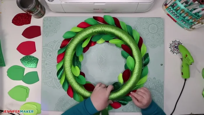 Create tri-fold leaves and glue them to the top of the wreath form in a V-shape (or W-shape for larger wreaths), overlapping and pointing slightly outward.