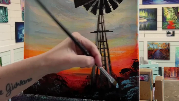 Paint the flowers: Use a filbert brush with a mix of blue and black to create flower petals, varying pressure and brushstrokes for different sizes and shapes.