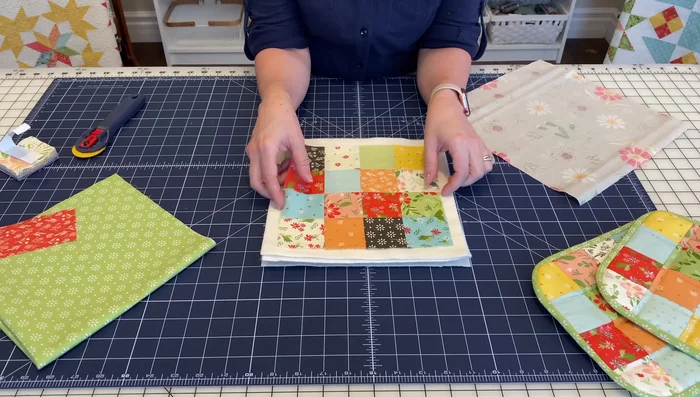 Assemble the potholder: Center the patchwork square on top of the batting and Insul-Bright sandwich. Place the 12x12 inch backing fabric (wrong side up) underneath.