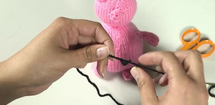 Embroider facial features using chain stitch. Secure the yarn at the back, work chain stitches, and fasten off by hiding the yarn end inside the stuffing.