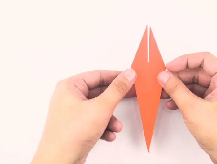 Fold the upper layer of the bottom point up so the bottom tip touches the top points. Fold the right flap over to the left, and repeat on the other side.