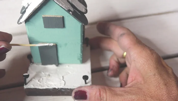 Apply snow: Apply the snow to the roof, base, door, and tree using a toothpick to create texture.