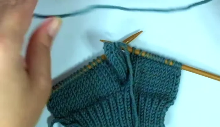 Attach yarn at the base of the thumb; pick up and knit one stitch on each side of the base of the thumb. 