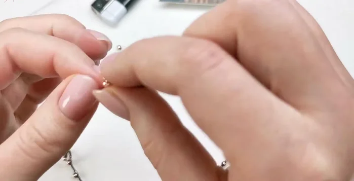 Add end beads: Add a weight bead to each end, tying a knot on the chain to secure it and melting the ends with a lighter to prevent unraveling.