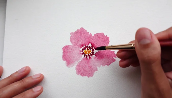 Go back in with the deep pink pigment and gently tap it into the center of the flower while the petals are still wet, allowing the color to bloom into the petals.
