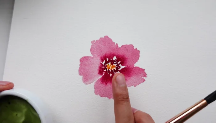 Add loose leaves with dark green paint while the petals are wet to create a blooming effect.