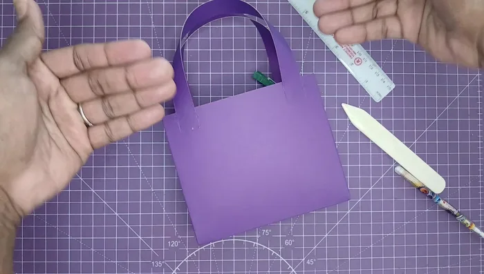 Layer decorative papers to enhance the handbag's appearance. Glue these layers in place.