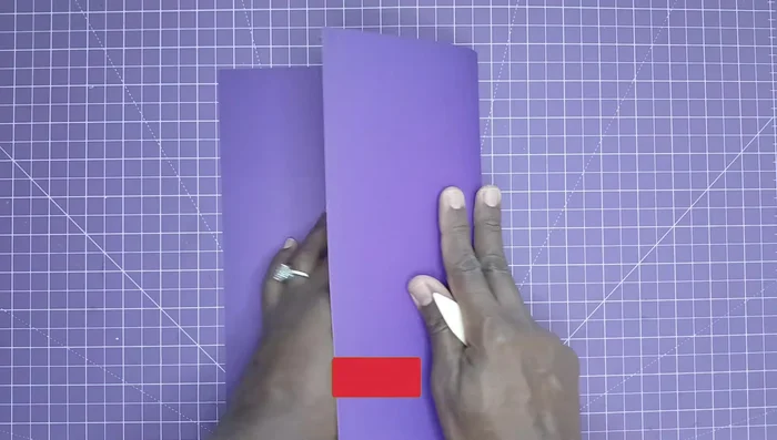 Perform the unique John B. Crops-inspired fold to create clean edges. Fold the paper in half, then bring the scored edges together to create a precise, clean crease.