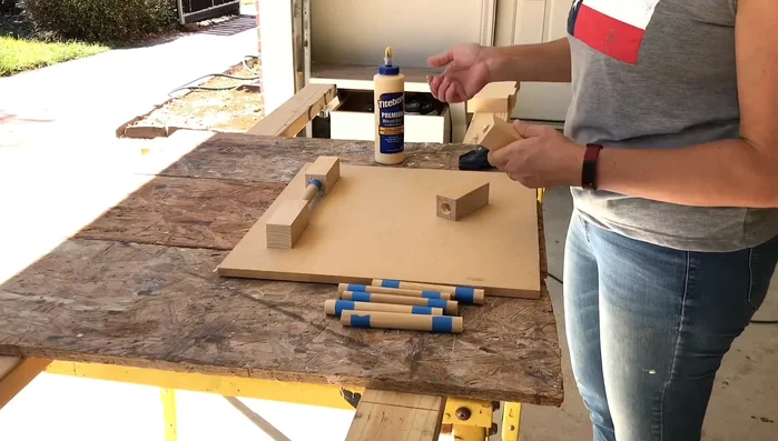 Insert the dowels into two of the blocks, ensuring even depth and using a flat board to keep them level while the glue dries.
