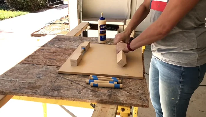 Insert the dowels into two of the blocks, ensuring even depth and using a flat board to keep them level while the glue dries.