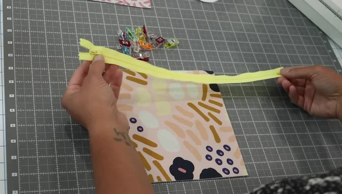 Attach Zipper to Exterior: Place the zipper face down on the right side of the exterior fabric, aligning it with the top edge. Leave extra zipper tape on each end. Baste the zipper to the fabric using a long stitch length (3mm).