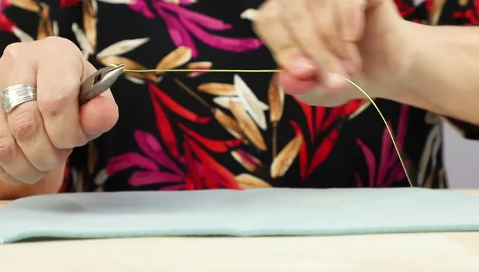 Create the earring hoop: Use a bottle to shape the 20-gauge wire into a hoop. Twist the ends together and flatten.