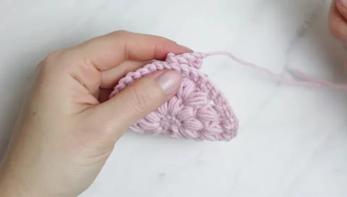 Fasten off and sew the strap to the opposite side of the scrubby (using the tapestry needle, sew through the front loops of the scrubby and entire stitches of the strap).