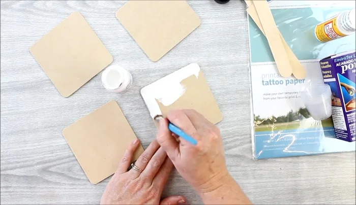Paint the coasters. Apply two coats of paint (e.g., chalk paint) to the front, back, and edges of the coasters, allowing each coat to dry completely before applying the next. (This step is crucial for the tattoo paper method to work properly)