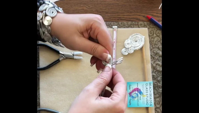 Continue rolling and flattening the wires, creating a swirl pattern. Keep pulling on both sides to maintain a flat shape.