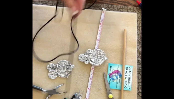 Cut 36 inches of 3mm rat tail and thread it through the loops of the pendant. Tie a knot and cinch it down to secure the pendant.