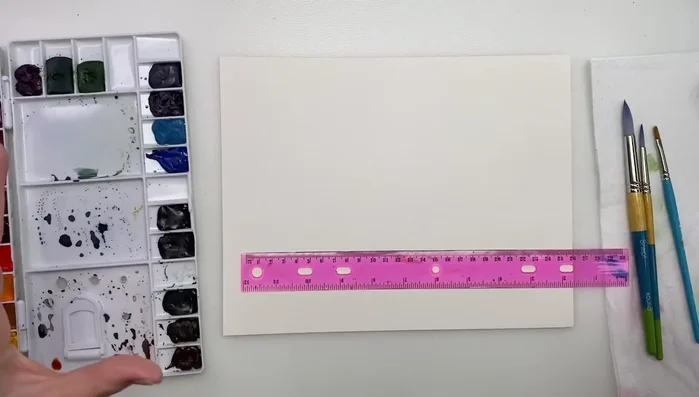 Sketching the house outline using a ruler to guide proportions.