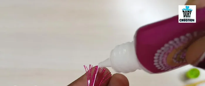 Glue and secure threads: Apply a small amount of fabric glue to the end of the thread. Place the thread onto the bangle and carefully press down to secure it. Repeat until all threads are glued onto the bangle, maintaining even spacing and ensuring the threads lie flat and even.
