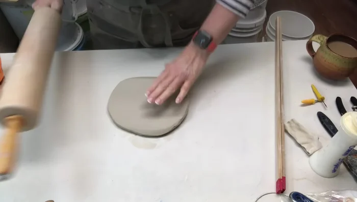 Ribbing both sides of the clay slab for strength and adding texture using a rib or a piece of wood.