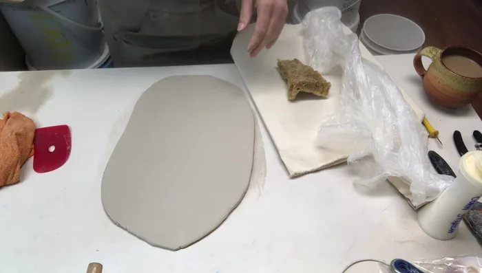 Ribbing both sides of the clay slab for strength and adding texture using a rib or a piece of wood.