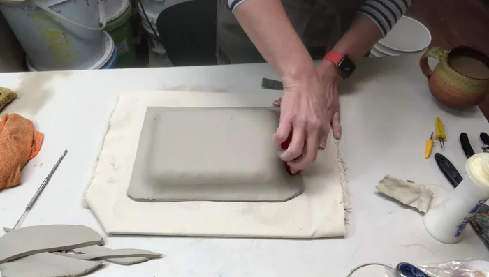 Trimming excess clay and making the edges even.