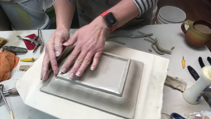 Smoothing out any gaps or tool marks with a wooden tool and a paint brush.