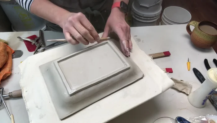 Smoothing out any gaps or tool marks with a wooden tool and a paint brush.