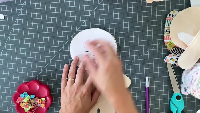 Embroider the face using a back stitch for the eyes, eyebrows, and mouth, and a satin stitch for the nose. Use three strands of embroidery floss.