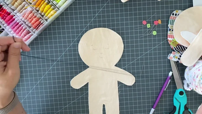 Embroider the face using a back stitch for the eyes, eyebrows, and mouth, and a satin stitch for the nose. Use three strands of embroidery floss.