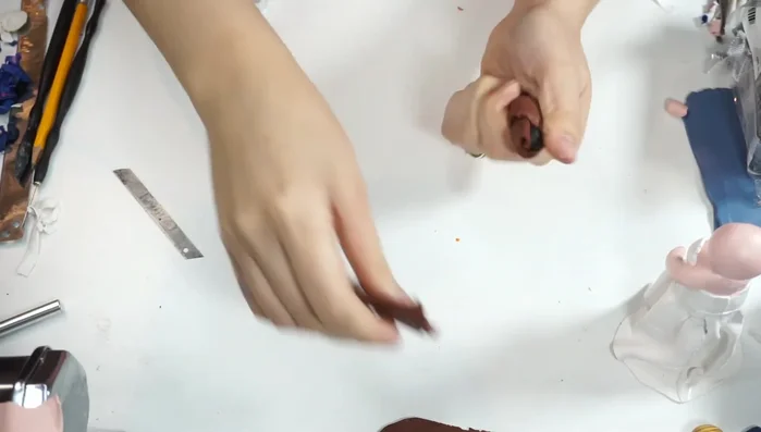 Create hair. Mix brown and black clay, load into the extruder, and use the smallest nozzle. Apply brown to the back of the heads, then add individual hair strands and curl them.