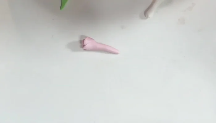 Add details. Make flowers and leaves from pink, white, and green clay for the bouquet. Attach using liquid polymer clay.